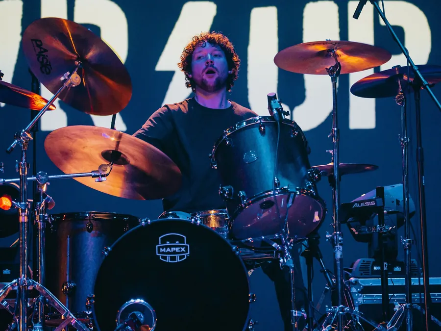 Andrew playing drums on stage under blue lights